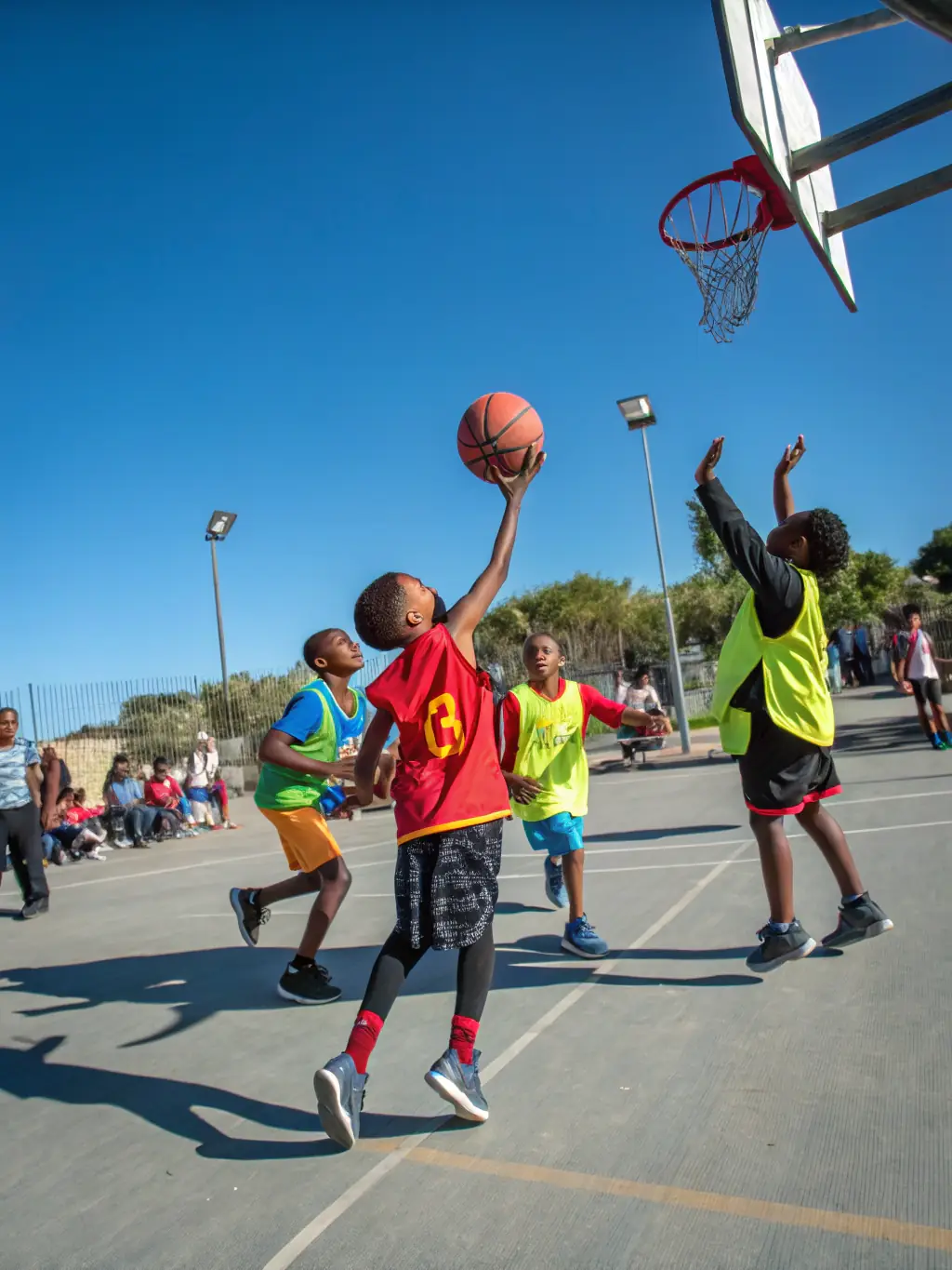 A group of diverse children laughing and playing basketball together in an inclusive sports program, showcasing the joy and camaraderie fostered by UCPA Sport Loisirs.